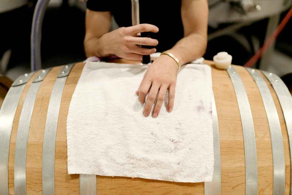 arms on a barrel siphoning wine